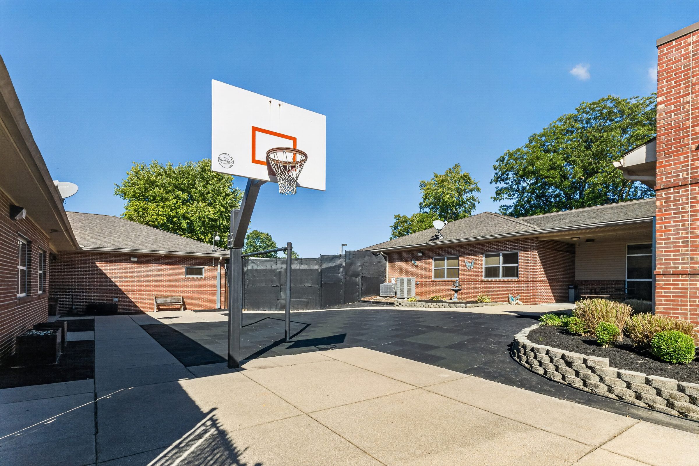 The enclosed courtyard at Golden Grove Recovery in Louisville with a basketball hoop and planted beds