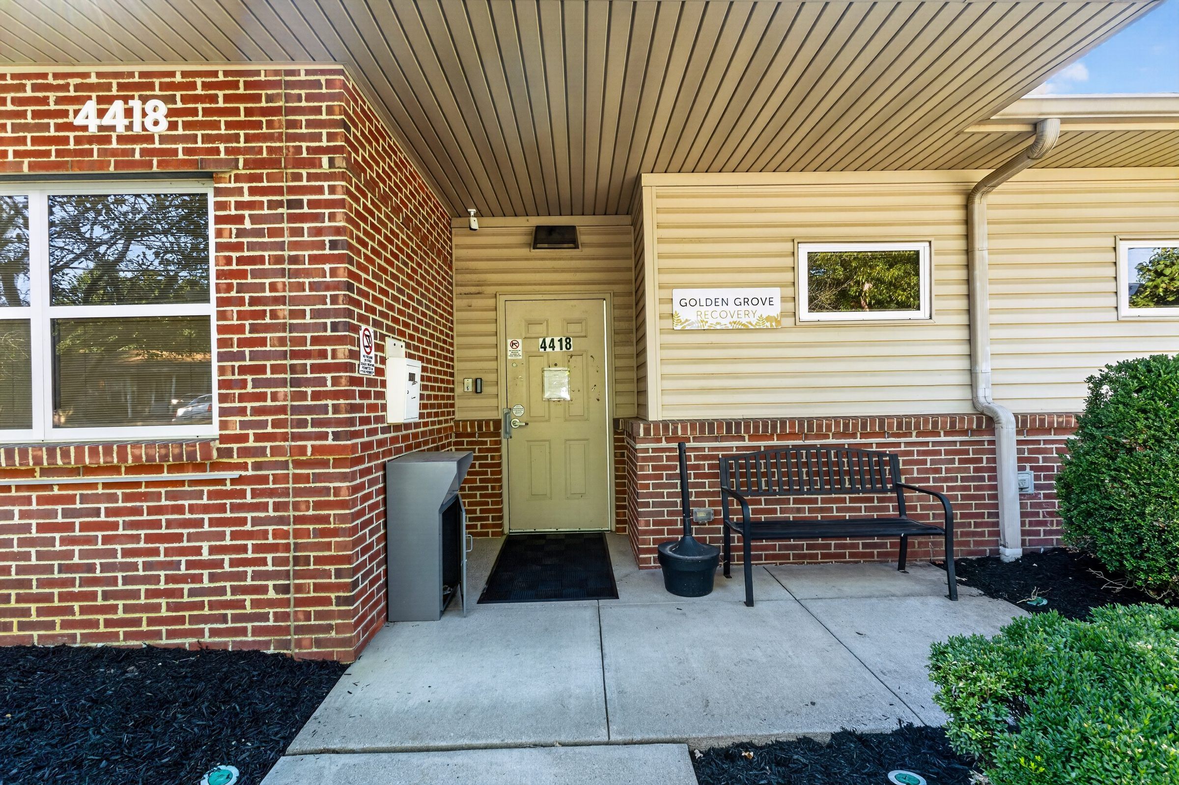 The front entrance of Golden Grove Recovery at 4418 Malcolm Ave, Louisville, with a bench under the covered walkway