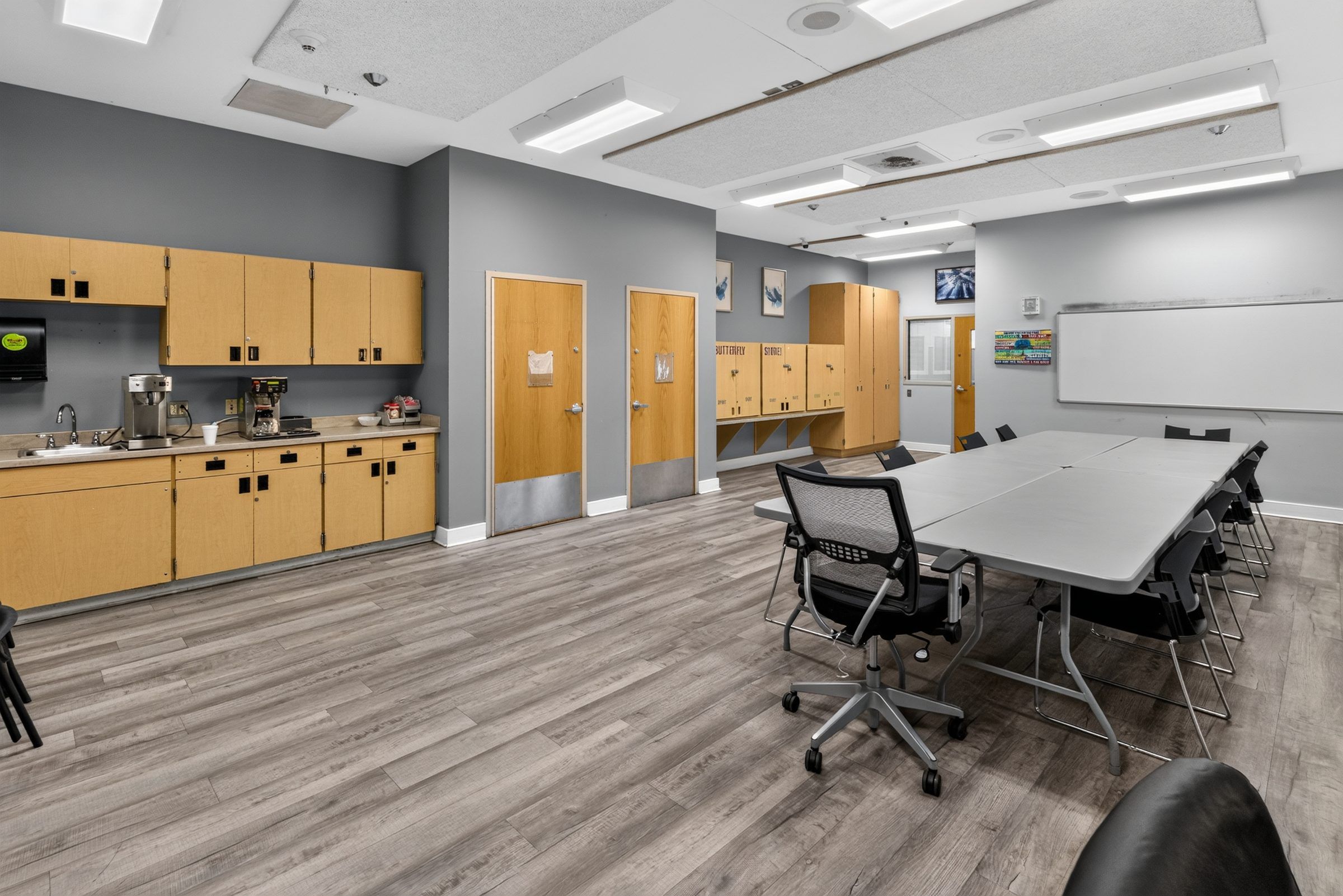 The kitchenette end of the long-table room at Golden Grove Recovery in Louisville, with cabinets, a sink and coffee makers