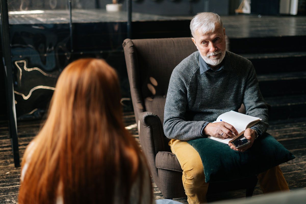A clinician seated in an office armchair, listening.