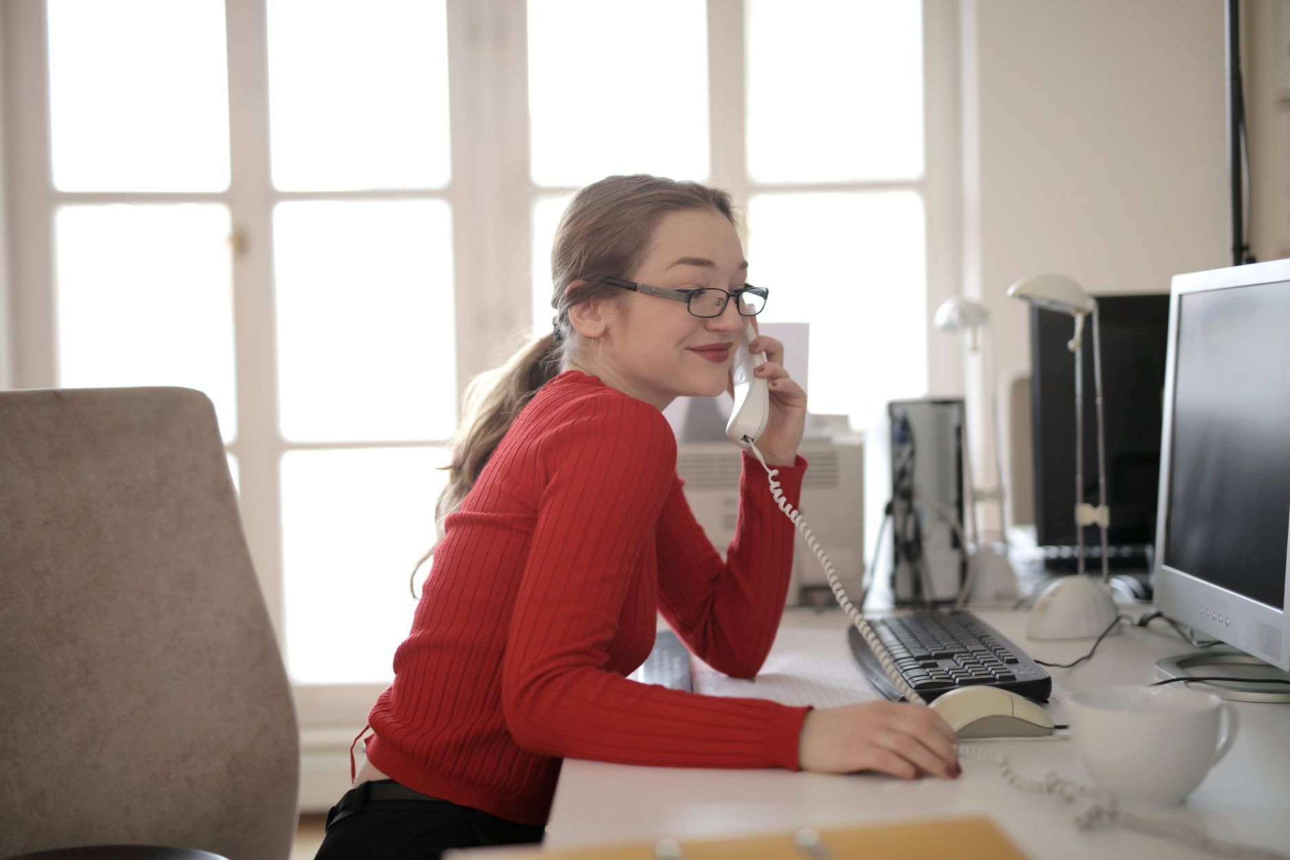 A coordinator at an office desk taking a phone call in daylight