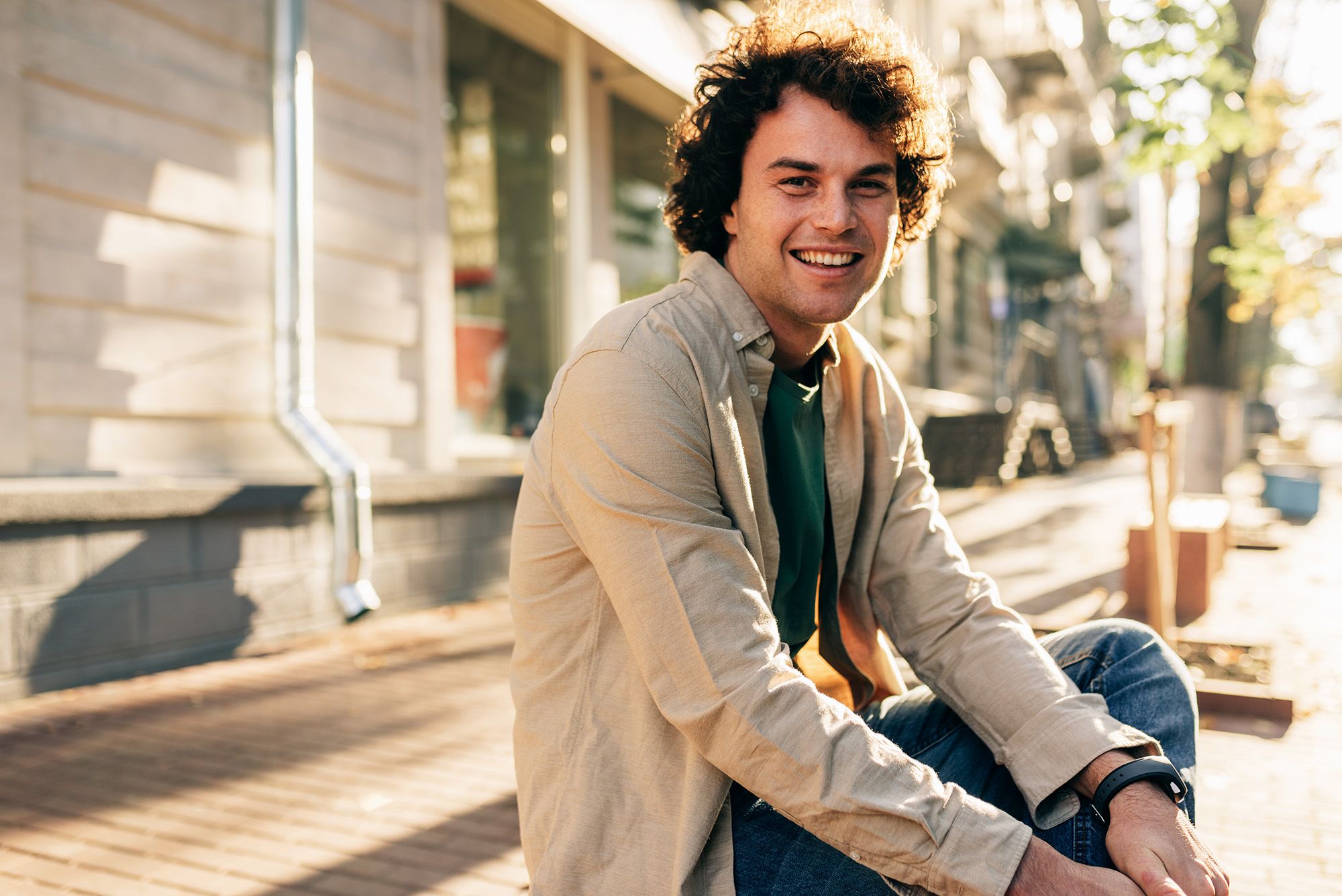 A man sitting outdoors in warm daylight, smiling